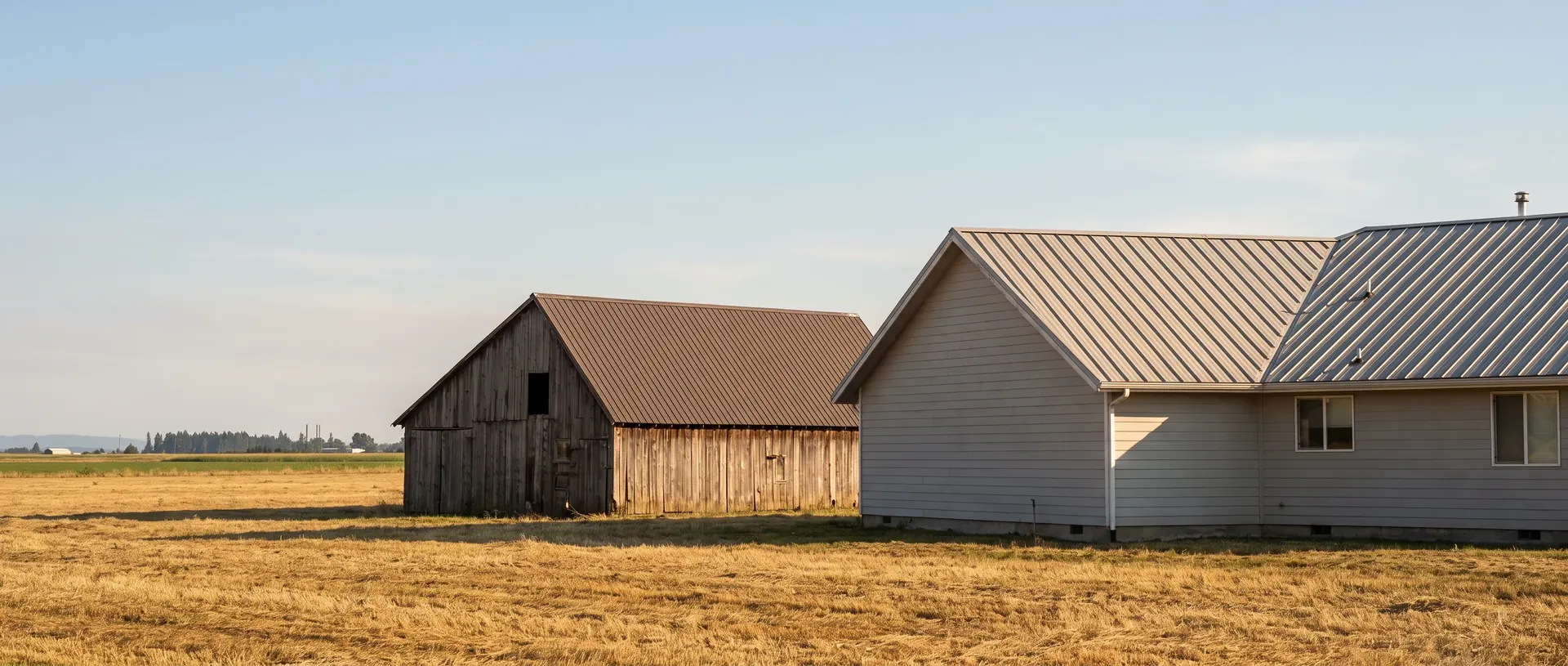 Ferndale house and farm outbuilding with metal roofs on open flat ground